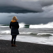 Frau einsam am Strand, dunkle Wolken