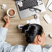 Erschöpfte Frau mit Kaffee, Laptop, Kopf auf dem Tisch