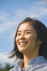 空をバックに笑顔の女性