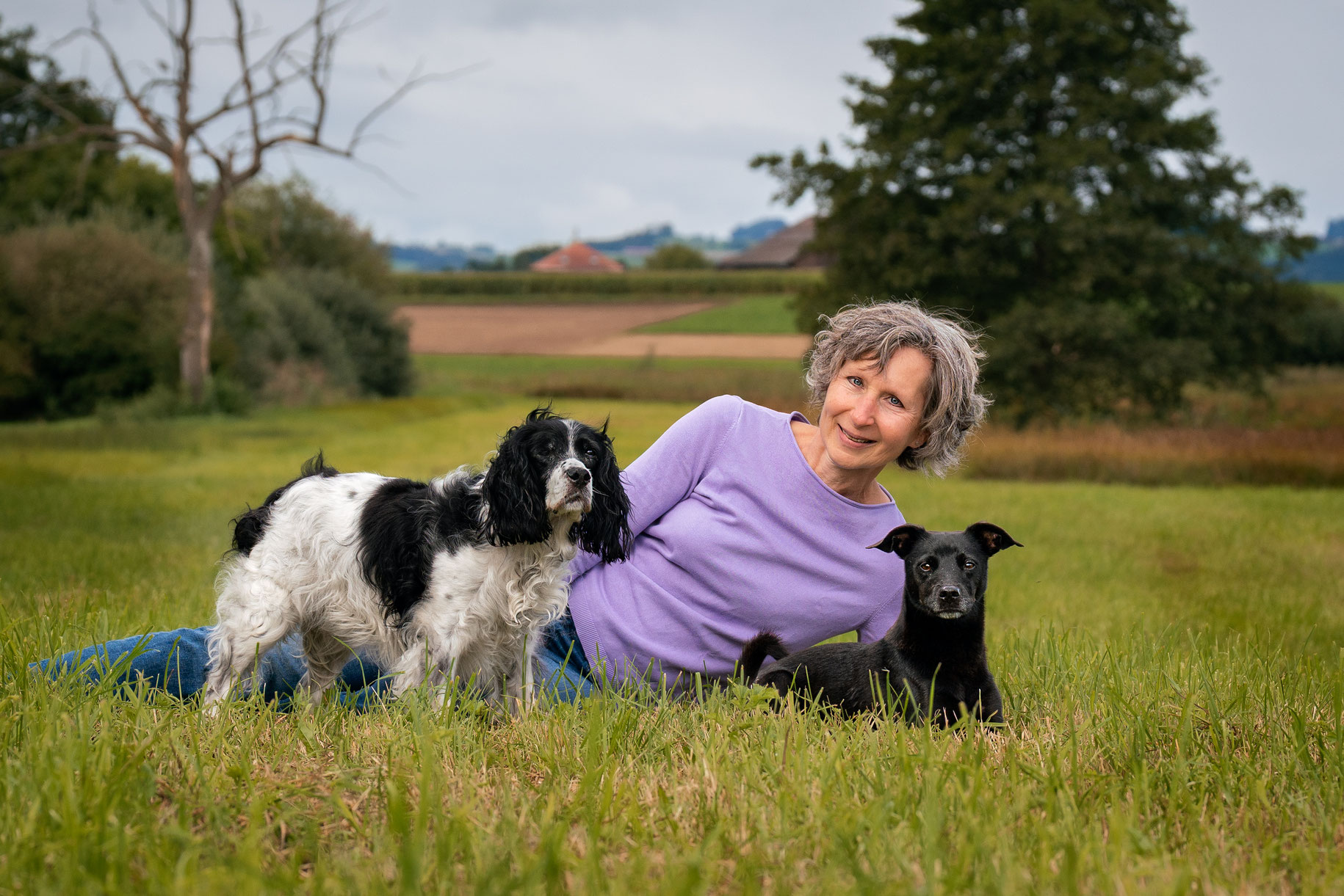 Frau liegend mit zwei Hunden im Gras