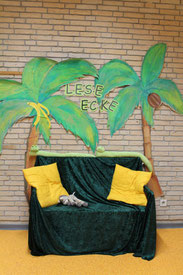 Leseecke mit gemütlichem Sofa vor Palmenbildern