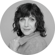 Porträt von Brigitte Lehner, Ontologische Kinesiologin und Cranio Fluid Dynamic-Practitioner – mit offenem Lächeln und sanfter Ausstrahlung, aufgenommen in heller, ruhiger Praxisatmosphäre mit frischen Tulpen im Vordergrund.