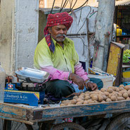 Vendeur de chikoo (fruit indien) assis sur sa cariole.