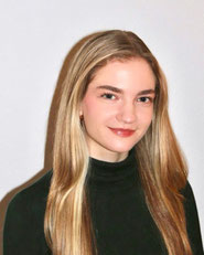 Portraitfoto von Veda Giesecke, vor einen weißen Hintergrund. Sie trägt einen schwarzen Rollkragenpullover und hat lange blonde Haare