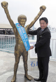 具志堅用高氏の銅像に国際ボクシング殿堂入りを記念してタスキを掛ける中山市長=25日午後、石垣港離島ターミナル