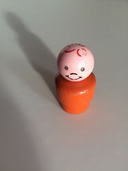 Photo d'un jouet en bois représentant un bonhomme qui sourit. Le jouet est seul sur fond gris. 