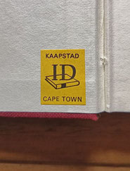 Das Bild zeigt einen kleinen, gelben Sticker mit der Aufschrift KAAPSTAD, CAPE TOWN
