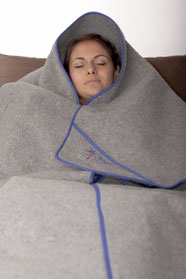 Person in eine OLM-Decke eingehüllt, liegend auf einem Sofa