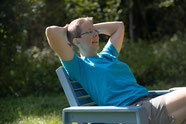 Foto einer Frau, die entspannt im Garten auf einem Stuhl sitzt