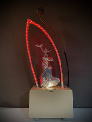 Skulptur ATARAXIE von Andreas Alka alias FLoYd mit roter LED-Beleuchtung, abstrahierte Figuren aus Draht auf lackiertem Sandstein, umschlossen von leuchtendem Plexiglasbogen.