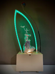 Skulptur ATARAXIE von FLoYd im grünen LED-Licht, bestehend aus Sandstein, Metalldraht und umschließendem Plexiglasbogen mit Farbwechsel.