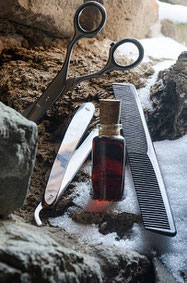 Schere,Kamm,Bartmesser und Bartöl, platziert zwischen Steinen mit Schneeresten, Coiffure Schneider