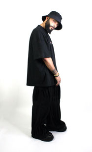 model wearing black bucket hat, printed black t-shirt and black wide pants