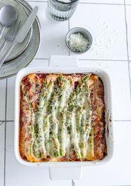 Spargel-Lasagne in einer weißen Auflaufform von oben fotografiert - grüner Spargel deutlich sichtbar unter goldbraunem geschmolzenem Mozzarella