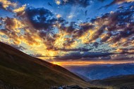 Vaste ciel au soleil couchant, mer de nuages derrière un versant de montagne