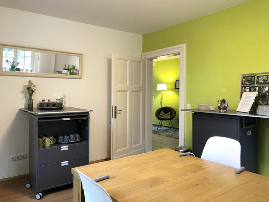 Holztisch und Sideboards mit Blick auf den Loungebreich mit Sofa.
