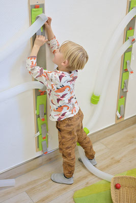 Kleines Kind spielt an einer Wand