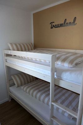 Ein freundliches Kinderzimmer mit Etagenbett und großem Fenster.