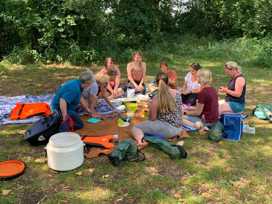 Foto der Teammitglieder beim Picknick im Schatten eines Baumes auf der Wiese.