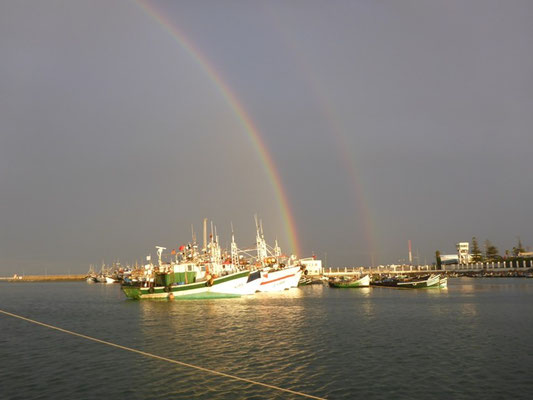 Regenbogen über den Fischer-Booten