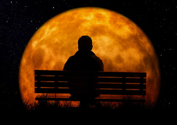 Die Silhouette eines Mannes auf einer Bank vor dem großen Mond als Symbol für tiefe innere Ruhe, Klarheit und die Einkehr im gereinigten Energiefeld.