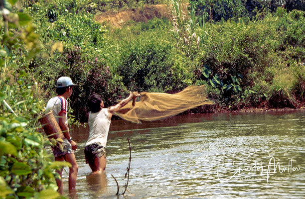 two young man throwing a casting net at Batang Ai River