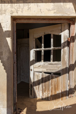 an entrance door to building in Kolmanskop blocked by the large amounts of sand