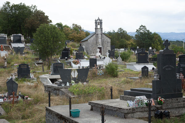 9.9. Unterwegs kommen wir an einem Friedhof vorbei. Auf den Gräbern fallen kleine Glaspyramiden auf, die Plastikblumen enthalten.