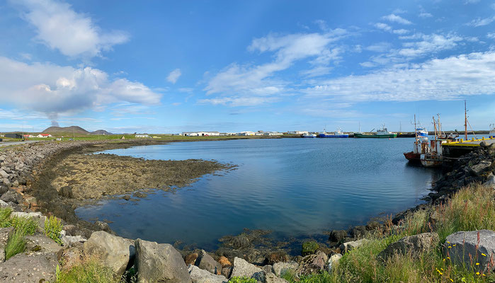 28.07. Wieder retour in Grindavík, spazieren wir zum Hafen. Im Hintergrund die Rauchsäule des Vulkans.