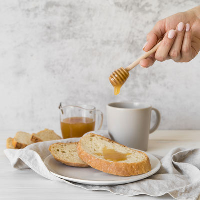 Petit déjeuner avec des tartines grillées sur les quelles il y a du Miel, on peut voir une infusion au Miel