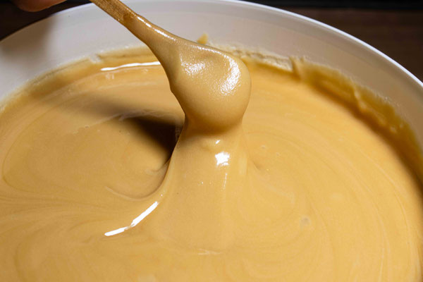 Photographie d'une cuillère en bois remplie de Miel de Thym de Nouvelle-Zélande de Puri New Zealand dans un seau de Miel de 10 kg pour les grossistes en Miel