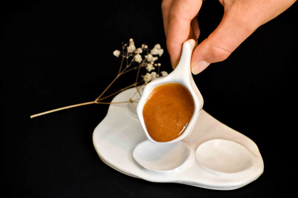 Jolie Photo d'une cuillère blanche en céramique dans la quelle se trouve du Miel de Manuka Haut de Gamme de Nouvelle-Zélande pour particuliers et grossistes