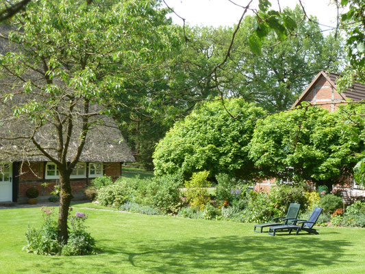 Im riesigen Garten finden sich diverse Plätze zum Entspannen, hier zwei Gartenliegen vor dem Staudenbeet.