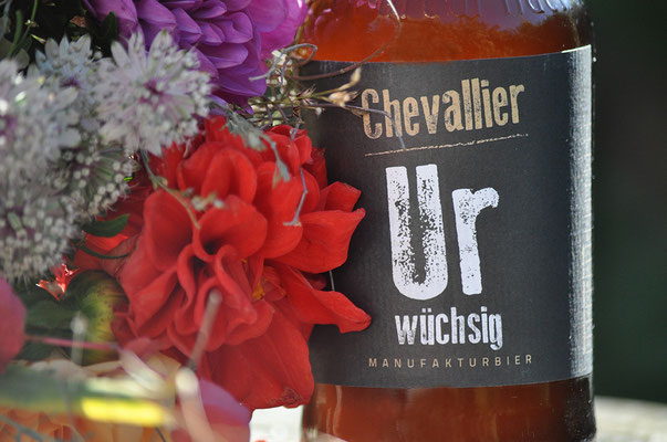 Fotografie eines Bieretiketts und einer roten Blume. Funkenflug Design aus Münster für "Münster Souvenirs".