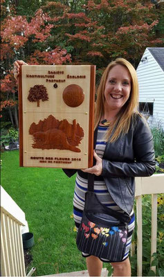 Madame Guyanne Fradette avec la plaque sculptée qui lui a été remise en reconnaissance du prix du plus beau jardin privé de la MRC de Portneuf en 2016.