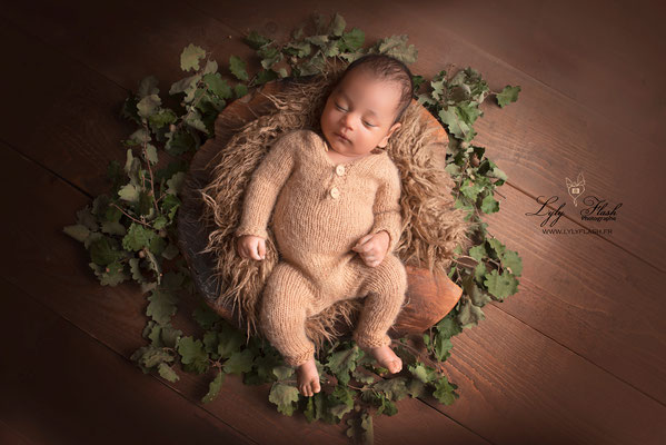bébé avec son pyjama de laine dort sur le dos dans un contenant en bois par Lyly Flash photographe nouveau-né