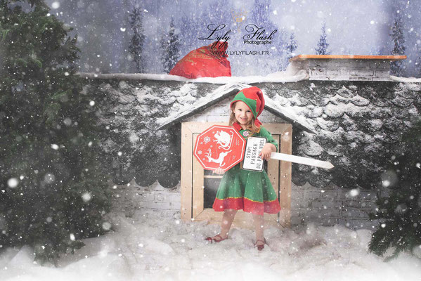Photo De Noël, portrait d'une petite princesse déguisée en lutin dans un décor grandeur nature à l'américaine. Quand le studio photo devient un parc de jeu pour enfant sur le thème de Noël 