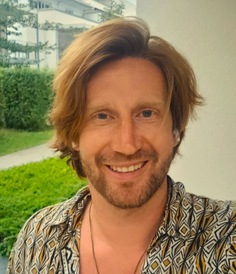 Maximilian Daschner steht lächelnd und kompetent vor einem Haus