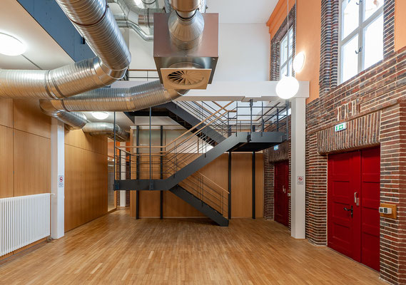 Sanierung und Umnutzung einer historischen Turnhalle zum Nachwuchsleistungszentrum, Foyer mit lufttechnischen Anlagen und Treppe