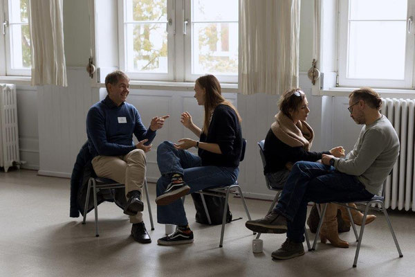 Momentaufnahme aus einem Workshop auf dem GFK-Tag Darmstadt: Vier Personen sitzen sich je zu zweit gegenüber und sind angeregt im Gespräch.