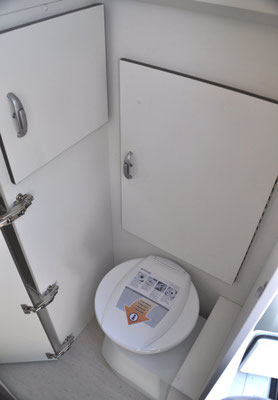 Dometic toilet, behind is large door for hanging space and left toiletry cupboard