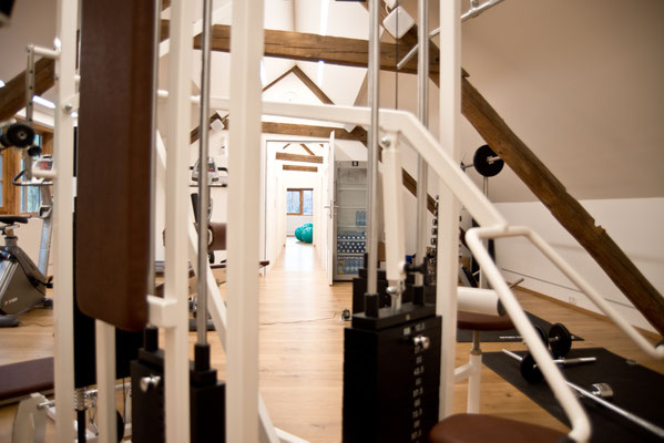 verschiedene Fitnessgeräte in einem freundlichen, hellen Raum