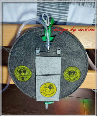 Beutelverstecker in anthrazit mit grauen Klickverschlüssen, aufgesetzter Tasche und handgemalten "Smiley-Motiv"
