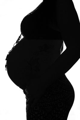 Silhouette einer schwangeren Frau im Profil vor hellem Hintergrund im Studio