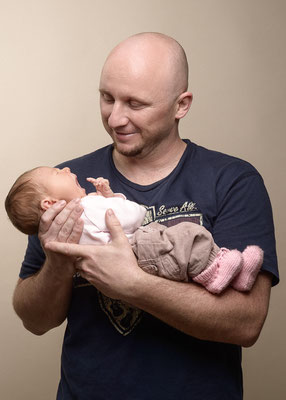 Vater hält sein Baby liebevoll im Arm, natürliche Babyfotografie in Villach