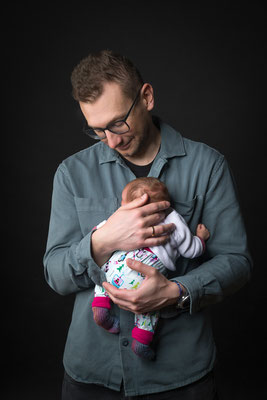 Vater hält sein Baby im Arm, ruhige Babyfotografie im Studio in Villach