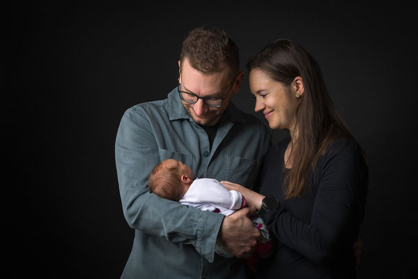 Eltern halten ihr Baby gemeinsam, natürliche Babyfotografie im Studio in Villach