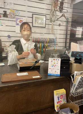 レジカウンターでラッピングをした商品を手に微笑む荒川京子さん