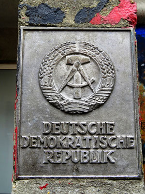 Sehenswürdigkeiten Berlin: Neben dem Mauermuseum wurden verschiedene ehemalige DDR-Artefakte an einer Wand angebracht. So z.B. das DDR-Hoheitszeichen, welches auf Grenzsäulen der innerdeutschen Grenze angebracht wurden.