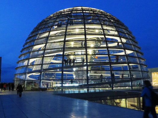 Sehenswürdigkeiten Berlin: Die von innen hell erleuchtete Glaskuppel auf dem Dach des Reichstagsgebäudes während der sogenannten blauen Stunde.